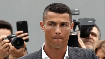 Portuguese footballer Cristiano Ronaldo surrounded by photographs looks on as he greets supporters outside the Juventus medical center at the Alliance stadium in Turin on July 16, 2018.