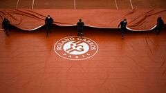 Operarios de Roland Garros tapan la pista.