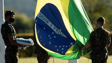 BRA100. BRAS&Iacute;LIA (BRASIL), 15/06/2020. - Soldados del Ej&eacute;rcito brasile&ntilde;o izan la bandera nacional este lunes en el Palacio do Alvorada, sede de la presidencia, en Brasilia. La batalla del coronavirus en Brasil, el segundo pa&iacute;s 