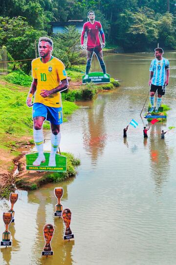 En la India ya se respira ambiente mundialista. Unos aficionados ondean banderas junto a unas siluetas gigantes de Neymar, Cristiano y Messi, con sus respectivas selecciones, en el ro Cherupuzha en Kozhikode, en el estado de Kerala. 