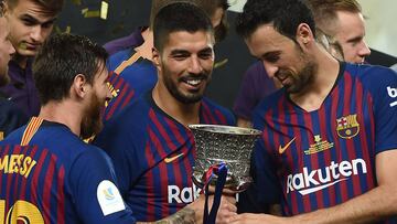 Barcelona's Argentinian forward Lionel Messi (2nd-L) presents the cup to Barcelona's Spanish midfielder Sergio Busquets (2nd-R) next to Barcelona's Uruguayan forward Luis Suarez (C) as they celebrate at the end of the Spanish Super Cup final between Sevilla FC and FC Barcelona at Ibn Batouta Stadium in the Moroccan city of Tangiers on August 12, 2018. - Barcelona defeated Sevilla 2-1 to win the Spanish Super Cup. (Photo by FADEL SENNA / AFP)