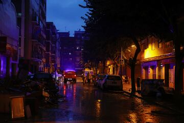 Un vehículo de la Unidad Militar de Emergencias (UME) pasa junto a dos personas que caminan bajo la lluvia, en Alfafar, Valencia.