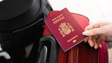 Unrecognizable female hand catches a Spanish European passport on luggage.