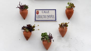 Street name in the town of Setenil de las Bodegas, Cádiz, Southern Spain. The street name is pasted on a white wall and surrounded by plants in clay pots. Image taken on a clear winter afternoon.