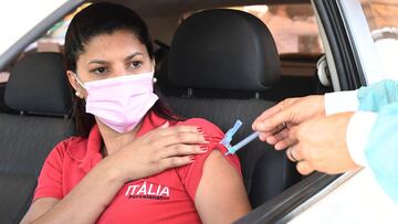 A woman receives a jab of the CoronaVac COVID-19 vaccine from a healthcare worker at a drive-thru vaccination post in Brasilia on September 13, 2021. - Brazil is one of the fastest vaccinating countries on the planet, after a late and chaotic start that continues to take its toll on President Jair Bolsonaro. (Photo by EVARISTO SA / AFP)