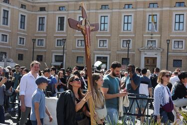 Una mujer lleva una cruz en la Plaza de San Pedro del Vaticano, tras la muerte del Papa Francisco.