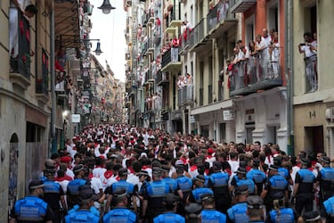 Agentes de policía observan a los participantes preparándose para correr delante de los toros antes del primer encierro de los Sanfermines en Pamplona.