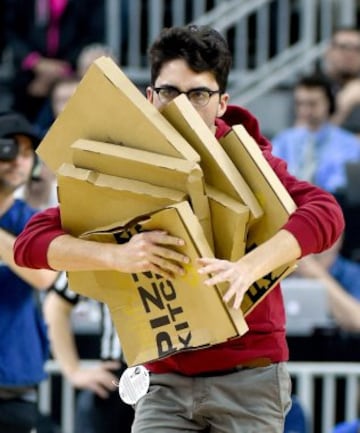 Un miembro de la banda de los USC Trojans corre con unas cajas de pizzas durante el descanso de los cuartos de final del Torneo Pac-12 de baloncesto. Los Trojans se enfrentaban a los UCLA Bruins.
