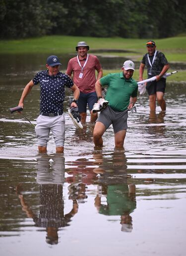 La lluvia se convirtió en protagonista del Abierto de Sudáfrica  investec de golf. En la imagen, los golfistas locales Jake Redman y Dean Burmester caminan por el agua que inunda gran parte del sexto hoyo en el Durban Country Club de Durban (Sudáfrica).
