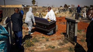 Relatives observe undertakers moving a casket containing the remains of a COVID-19 coronavirus patient during a funeral at the Avalon cemetery in Soweto, on July 24, 2020. (Photo by Michele Spatari / AFP)