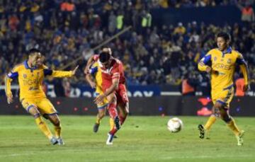 Los jugadores de Tigres Junior Anselmo (i) y Hugo Ayala (d) disputan el balón con Enrique Triverio (c) de Toluca durante el partido de ida de las semifinales del Torneo Apertura del fútbol mexicano, realizado en el estadio Universitario.