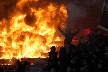 Los aficionados del Partizan animan frente a asientos en llamas durante un derbi de la liga nacional de fútbol de Serbia entre el Estrella Roja y el Partizan en Belgrado.