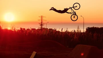 El piloto de MTB Bienvenido Aguado en La Poma Bikepark (Premià de Dalt, Barcelona, España) al amanecer, con las cañas, el mar y el sol de fondo.