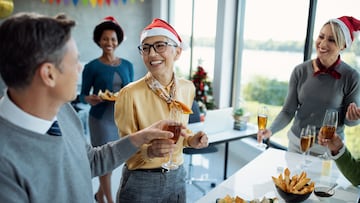 Happy mature businesswoman having glass of Champagne while celebrating with colleagues on Christmas party in the office.