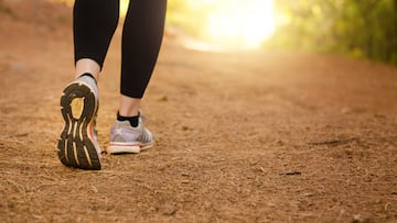 Pair of legs walking on a trail in nature towards the light