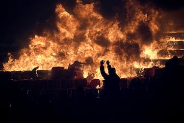 Los aficionados del Partizan animan frente a asientos en llamas durante un derbi de la liga nacional de fútbol de Serbia entre el Estrella Roja y el Partizan.