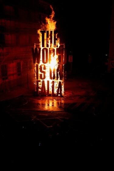 Una estructura de palabras que dice "El mundo está en Falla" arde durante las Fallas en Valencia.