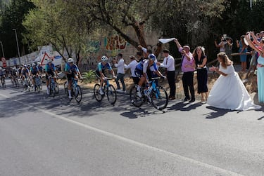 Para una novia el día de su boda es algo inolvidable. Más aún si tiene ocasión de vivir in situ una etapa de La Vuelta. La protagonista de la foto decidió animar a los corredores durante la jornada, igual que los asistentes al enlace. Alguno, incluso, cambió el teléfono para inmortalizar el momento por una cerveza para evitar la deshidratación.