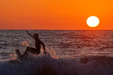 Un surfista monta una ola en el ocaso del día en California, donde esta actividad es muy popular en toda su costa, siendo incluso deporte oficial del estado, y ofrece olas para todos los niveles. El otoño suele ser una excelente época para surfear,  por la combinación de vientos y olas. La foto es de Encinitas, un lugar atractivo para los amantes de este deporte.