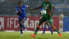 Toni Varela y Kondwani Mtonga pelean un bal&oacute;n bajo la lluvia en el Zambia-Cabo Verde.