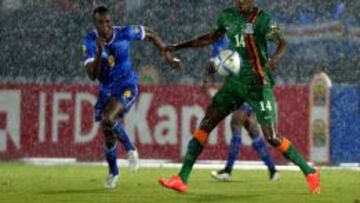 Toni Varela y Kondwani Mtonga pelean un bal&oacute;n bajo la lluvia en el Zambia-Cabo Verde.