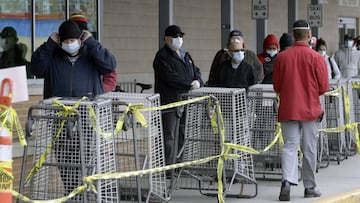 Las personas usan una m&aacute;scara mientras esperan a una distancia segura para ingresar a un supermercado, el lunes 20 de abril de 2020, en Chelsea, Massachusetts.