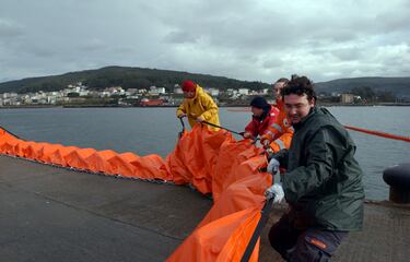 Un grupo de obreros preparan una segunda barrera para proteger el puerto de Corcubión del petróleo derramado.
