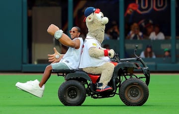 La mascota de los Atlanta Braves Blooper traslada al rapero Ludacris, que realizó el saque de honor en el partido de la liga estadounidense de béisbol (MLB) que el equipo disputó contra los Colorado Rockies. Ludacris balanceó sus enormes brazos y su reloj, reconocibles para los aficionados por su vídeo musical Get Back, de 2005.