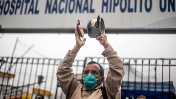 A health worker bangs a pot during a protest against the lack of security equipment, outside the Hipolito Unanue public hospital in Lima on May 20, 2020, amid the new COVID-19 coronavirus pandemic. (Photo by ERNESTO BENAVIDES / AFP)