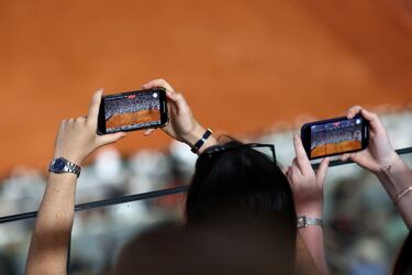 Dos aficionadas graban en vídeo, con sus teléfonos móviles, el partido de segunda ronda de Roland Garros entre Carlos Alcaraz y el neerlandés Jesper de Jong, en la pista Philippe Chatrier. Desde que iniciase su participación en el torneo francés, ante Wolf, Carlitos se ha convertido en uno de los principales centros de atención del público. 