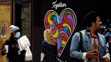 People walk past a mural displayed outside a store amid the coronavirus pandemic on May 19, 2020 in Washington, DC. (Photo by Olivier DOULIERY / AFP)