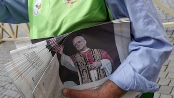 A volunteer holds copies of the L'Osservatore Romano newspaper, containing a photograph of newly elected Pope Leo XIV, as seen from Rome, Italy, May 9, 2025. REUTERS/Murad Sezer