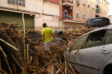 La gente camina por calles cubiertas de barro y escombros entre coches amontonados después de que las inundaciones repentinas afectaran la región el 30 de octubre de 2024 en Valencia, España