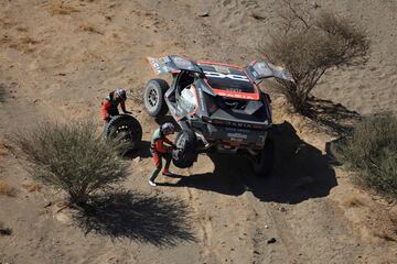 El piloto qatarí Nasser Al-Attiyah y su copiloto Edouard Boulanger reparan su coche tras un pinchazo durante la etapa 2B del 47º Rally Dakar.