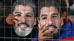 Fans of Nacional hold masks with an image of Uruguayan football star Luis Suarez during a campaign to try to convince him to return to the club, before the start of the Uruguayan First Division match between Nacional and Cerrito at the Gran Parque Central stadium in Montevideo on July 21, 2022. - A massive campaign on social networks has expanded in Uruguay so that the Uruguayan idol Luis Su�rez returns to Nacional, the club of his beginnings before acquiring world fame. Under the hashtag #Su�rezANacional, fans of Nacional are trying to convince him to join the club until the World Cup. (Photo by Pablo PORCIUNCULA / AFP)