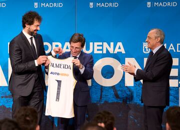 El jugador del Real Madrid, Sergio Llull, entrega una camiseta del equipo al alcalde José Luis Martínez-Almeida
mientras el presidente del equipo, Florentino Pérez, aplaude. 