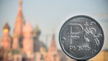 A Russian ruble coin is pictured in front of St. Basil's cathedral in central Moscow, on April 28, 2022. - A Russian official said Thursday that the ruble will soon be introduced in areas of Ukraine under Moscow's control, despite Russia earlier insisting it was not seeking to occupy captured territory. A civilian and military administrator of the Russian-controlled region of Kherson in southern Ukraine said Moscow would introduce its currency in the region within the coming days. (Photo by Alexander NEMENOV / AFP)