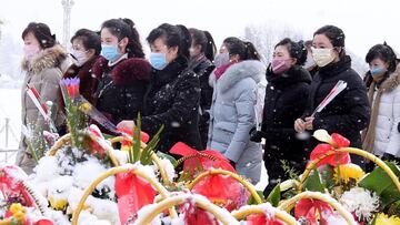 Varios ciudadanos de Corea del Norte posan con mascarillas delante de las estatuas de Kim Il Sung y Kim Jong Il en Pyongyang.