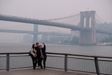 Un grupo de turistas se hacen un autorretrato en con el fondo del puente de Manhattan y el puente de Brooklyn, a la derecha.