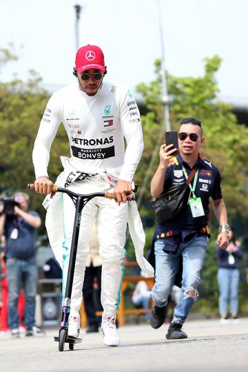 El piloto británico monta en un patinete eléctrico en el paddock.