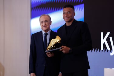 El delantero francés del Real Madrid Kylian Mbappe posa junto al presidente del club, Florentino Pérez, tras recibir este viernes la Bota de Oro en un acto celebrado en el palco del Santiago Bernabéu.