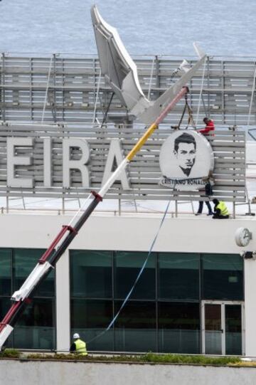 Workers add a sign bearing Cristiano Ronaldo's face to the airport exterior ahead of its 29 March name change to Madeira Cristiano Ronaldo Airport.