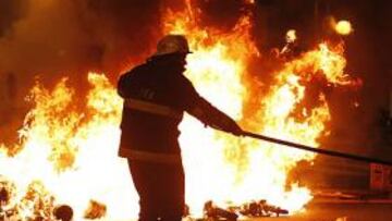 <b>EL INFIERNO. </b>Un bombero intenta apagar el incendio provocado por los aficionados de River después de que se consumara el descenso de su equipo.