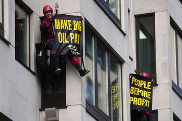 Activistas ambientales sostienen pancartas mientras escalan el frente del Hotel InterContinental durante la protesta Oily Money Out, en Londres.

