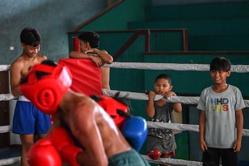 Un par de niños observan a dos jóvenes que están entrenando en el ring. 
 