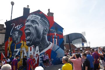 Crystal Palace fans pose for a picture in front of Wilfried Zaha's mural outside Selhurst Park.