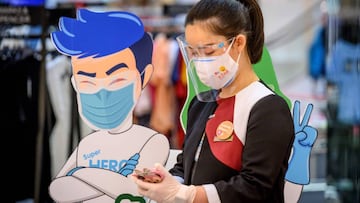 An employee wearing a facemask and a shield looks at her phone at the Central World shopping mall as it reopened after restrictions to halt the spread of the COVID-19 coronavirus were lifted in Bangkok on May 17, 2020. (Photo by Mladen ANTONOV / AFP)