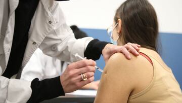 A doctor administers a Pfizer-BioNTech Covid-19 vaccine to a woman during the night of January 8, 2022 in the recently opened 24 hours Covid-19 vaccination centre in Sarrola-Carcopino on the French Mediterranean island of Corsica. (Photo by Pascal POCHARD-CASABIANCA / AFP)