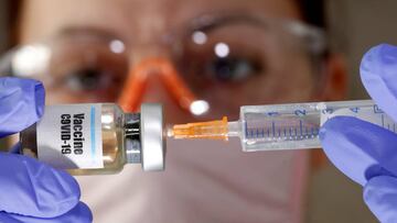 Una mujer coge un frasco con el rótulo de vacuna contra el coronavirus.