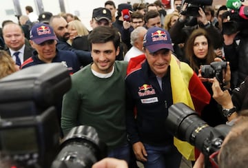 Los campeones de coches del Dakar 2018 llegaron al aeropuerto de Madrid en medio de una gran expectación y de decenas de seguidores que les vitorearon a su llegada. En la foto Sainz con hijo. 